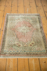 Distressed pile texture, blue meandering vine border, and dusty rose tones on a vintage Oushak.
