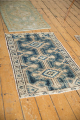 Distressed vintage Northwest Persian rug corner, showing indigo, beige, and brown geometric border.