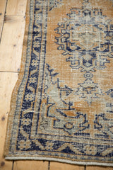 Distressed Oushak border in pale gold, cobalt blue, silver, with exposed knot heads.
