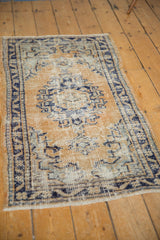 Distressed vintage Oushak rug corner, with pale gold and cobalt blue motifs, visible foundation.