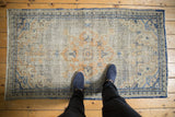Vintage distressed Oushak runner with faded scalloped medallion and intricate blue border.