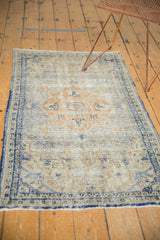 Textured distressed pile and secured denim blue border of a vintage Turkish Oushak rug.