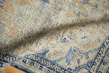 Textural close-up of distressed Oushak rug pile, showing worn knots and denim blue, ivory tones.