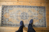 Distressed Oushak rug runner with a pale gold field, cobalt blue medallion, and fine vinery.