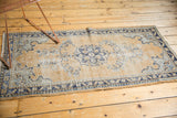 Vintage Oushak runner with an evenly worn pale gold field and faded blue decorative motifs.