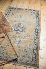 Distressed Oushak rug's textured pile, revealing faded dusty gold and cobalt blue.