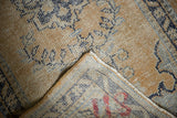 Vintage Oushak runner's distressed dusty gold pile and reverse foundation with red markings.