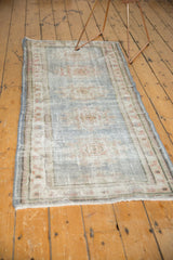 Distressed pile of a vintage Oushak runner, featuring muted pale blue, ivory, rose.