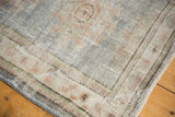 Secured corner of a distressed Oushak rug runner, revealing pale blue, ivory, and rose texture.