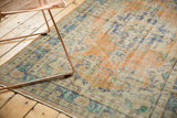 Oushak rug's distressed pile texture, revealing faded saffron yellow, blue, and mint green.