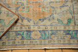 Distressed vintage Oushak rug close-up, showing even wear across saffron, ivory, and blue pile.