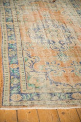 Distressed texture and worn pile of a vintage Oushak rug with faded saffron, blue, and mint.