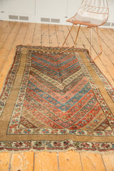 Antique Kurdish rug's floral chevron field, unique plain camel border, and time-softened fringe.