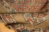Antique Kurdish rug detail: wide camel border contrasting with red and blue floral motifs.