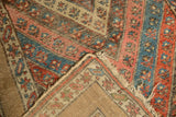 Madder red, sky blue, and camel floral stripes on a Kurdish rug, highlighting a wide, plain border.