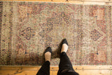 Antique Kerman runner featuring scalloped medallion, floral field, and overall wear.