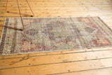 Machine-bound side edge of the antique Kerman rug, revealing perimeter wear and loose areas.