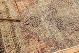 Close-up of antique Persian Kerman rug, revealing scalloped medallions, cochineal red floral blossoms, and knot head wear.