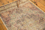 Antique Persian Kerman runner with scalloped medallions, floral blossoms, and visible pile wear.