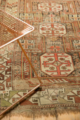 Antique Caucasian rug's geometric rams horn medallion, with infinity knots in rust, ivory, and charcoal.