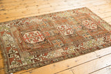 Antique Caucasian rug corner, geometric patterns in copper, rust, ivory, charcoal brown, with tattered edge.