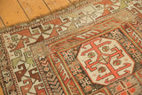 Worn fringe and geometric copper, rust, charcoal, ivory patterns on antique Caucasian rug.