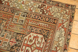 Close-up of geometric arabesque border and tattered side of antique Caucasian rug.