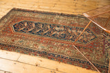 Rust, navy, and ivory stepped floral patterns with visible border wear on vintage Hamadan rug.