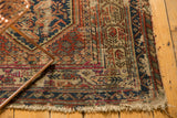 Vintage Hamadan rug's frayed fringe and Serbend border in rust and navy blue.