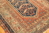 Stepped blossomed florals on navy field, rust border with germinating boteh, and visible wear.