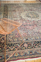 Detailed navy border of the Persian Meshed carpet with faded plum and sky blue floral patterns.