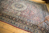 Vintage Meshed rug's navy border and faded plum field, featuring floral vinery and low pile wear.