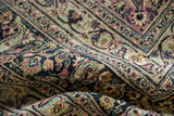 Close detail of traditional Persian Meshed rug, folded, displaying plum, navy, and sage vinery.
