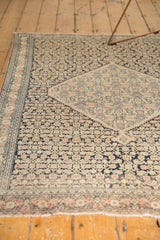 Antique Senneh rug corner showing fringed end, inverted Herati motif in dark navy, ivory, blush.