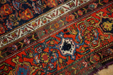 Cherry red field of vintage Malayer carpet, staggered floral motifs, ivory border, visible end wear.