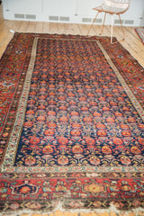 Vintage Malayer carpet corner, showing staggered navy floral motifs and fringe wear.