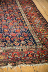 Vintage Malayer carpet's navy field with staggered floral design, red border, and worn fringe.