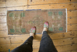 Distressed vintage Oushak runner showing worn apricot and mint green motifs, textured pile, and blue edge.