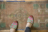 Distressed Oushak rug showing even wear to knot heads and muted apricot, mint patterns.
