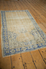 Corner of distressed vintage Oushak rug, highlighting worn texture and sky blue geometric border.