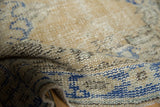 Distressed vintage Oushak rug pile showing even wear, beige, sand, and sky blue hues.