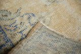 Worn pile and secured edge of a vintage Distressed Oushak rug, with blue foundation.