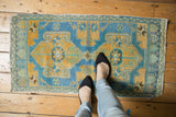 Distressed vintage Oushak rug in muted blue, gold, and teal underfoot.