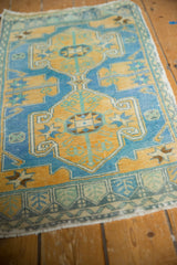 Distressed gold and sky blue Oushak rug, showing starburst and scrolling ram's horn motifs.