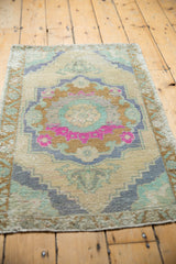 Distressed Oushak rug detail: central medallion with pink, mint, and grey-blue motifs, showing pile wear.