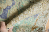 Distressed vintage Oushak rug edge revealing worn pile and visible ivory foundation.