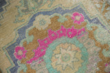 Vintage distressed Oushak rug detail: bubble gum pink and mint green geometric pattern.