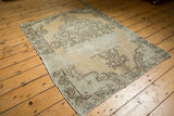 Corner of the vintage distressed Oushak rug, showing faded beige vinery and worn foundation.