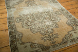 Texture of the distressed vintage Oushak rug, showing wear and muted floral patterns.