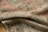Distressed Oushak rug pile showing even wear to knot heads in muted pink and ivory.